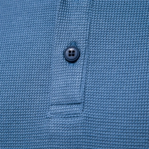 Macro de la texture gaufrée bleu marine et du bouton sur le t-shirt à manches longues