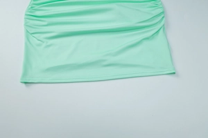 Detailed view of mint green dress with stylish ruched fabric texture and pleated design