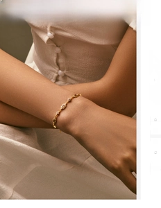 Detail view of a vintage gold bracelet with ruby red gemstones on a model's wrist