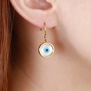 Detailed view of gold plated Evil Eye earrings with blue center on female model