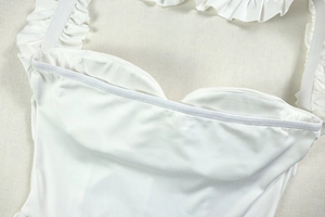 Close-up of white ruffled dress with elastic pleated straps and refined stitching detail