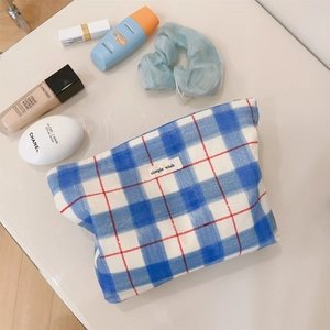 Detailed top view of blue checkered canvas makeup bag with small red grid accents