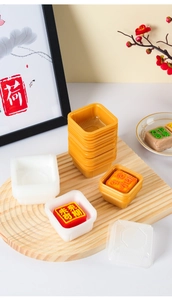 Square food-grade plastic mooncake trays in gold and white stacked on a wooden plate