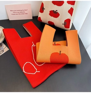 Flat lay of colorful knitted tote bags with fruit patterns on dark background