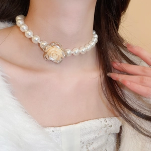 Detail of multi-layer pearl necklace with a diamond-encrusted yellow rose pendant