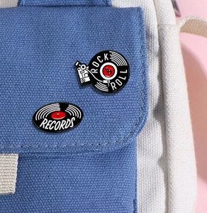 Close-up of Rock Roll and Records enamel pins on a blue canvas bag with pink background