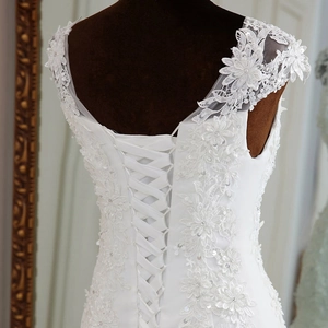 Detail of white bridal gown with floral lace appliques and corset lace-up back design