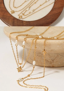 Close-up of layered gold stainless steel necklace with pearls and star pendants
