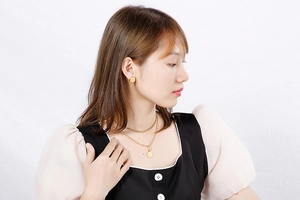 Detailed view of multilayer titanium steel necklace and gold stud earrings set on model
