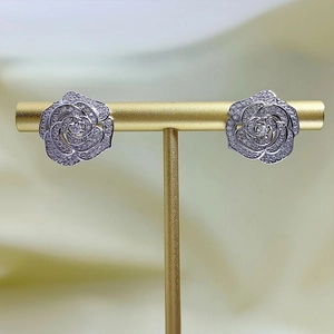 Detailed close-up of camellia stud earrings with sparkling white zircons on a T-stand