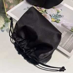 Detailed view of the black satin drawstring bag on a magazine with elegant reflection