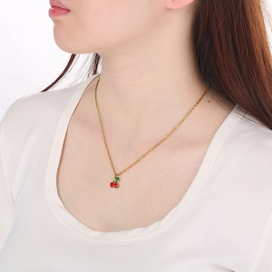 Dettaglio di una collana con ciondolo a ciliegia rossa indossata da una modella
