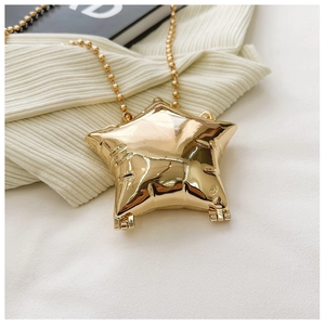 Detailed close-up of shiny gold star-shaped mini crossbody bag with bead chain