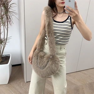 Close-up of khaki plush heart-shaped crossbody bag with decorative silver chain strap