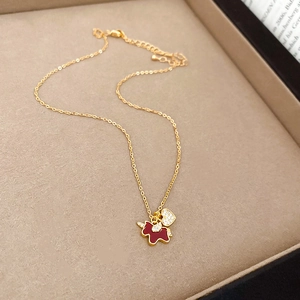 Macro detail of gold-plated necklace with red enamel unicorn and sparkling heart pendant