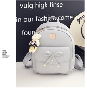 Close-up of grey PU leather backpack with bow detail and cute teddy bear charm