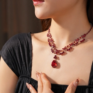 Detail of red water-drop pendant necklace with zircon floral accents on a model