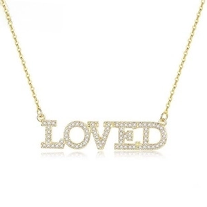 Macro detail of gold stainless steel necklace with 'LOVED' pendant and white zircons