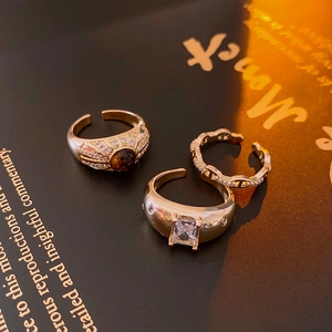 Detailed view of vintage gold rings with zircon and brown stone on a dark book