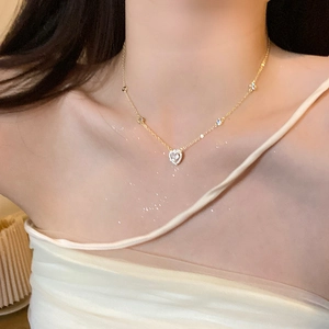 Primo piano di una collana a cuore dorata con cristalli scintillanti su una modella