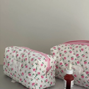 Detail of two floral quilted velvet makeup bags with pink zippers and diamond stitching