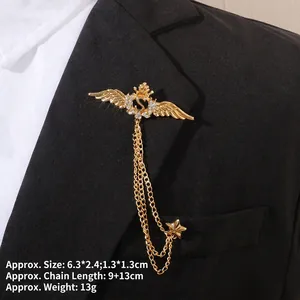 Détail d'une broche couronne dorée avec initiale S et chaînes sur un revers noir
