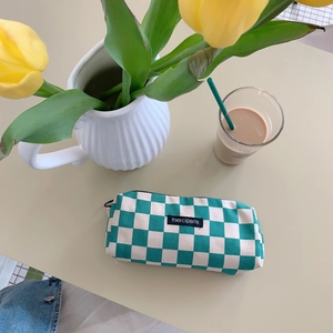Detail view of green checkerboard corduroy pencil case with a merciparis woven label