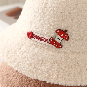 Vue détaillée d'un chapeau cloche en peluche crème avec patch pomme et ruban brodé