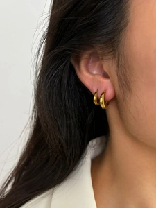 Gros plan de créoles dorées en forme de larme avec finition polie sur l'oreille
