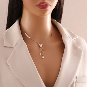 Detail of gold butterfly necklace with multilayered pearl tassels on a blazer model