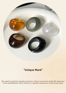 Detail shot of chunky resin rings in amber, green, and tortoiseshell on a white tray