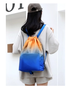 Rear view of model wearing a gradient orange to blue waterproof drawstring backpack