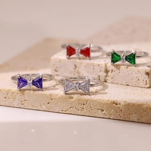 Chic silver bow rings set with vibrant purple, red, and emerald green faceted gemstones