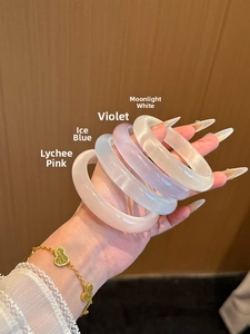Détail de bracelets en pierre d'œil de chat translucide aux tons pastel et chaîne dorée