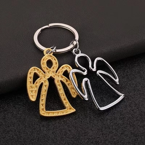 Dual-tone angel metal keychain pendants with hollow texture on dark leather background