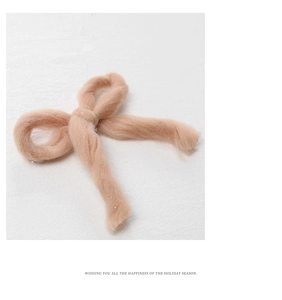 Macro detail of soft honey pink felt wool Christmas bow with cozy knitted texture