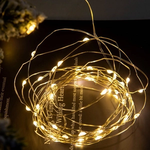 Warm white LED copper wire fairy lights coiled on dark surface for festive decoration