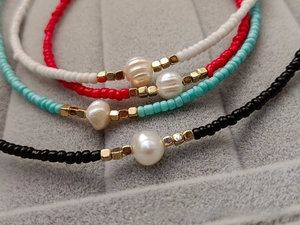 Detailed macro view of colorful beaded necklaces with freshwater pearls on grey velvet tray