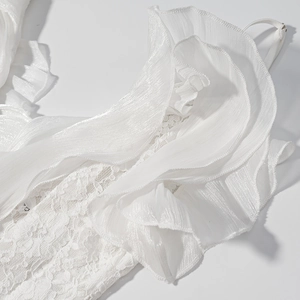 Détail de la dentelle blanche superposée et des volants en tulle à paillettes