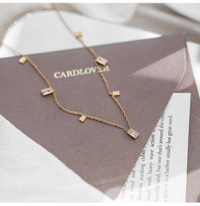 Detailed close-up of French luxury titanium necklace with square crystal tassels and gold chain