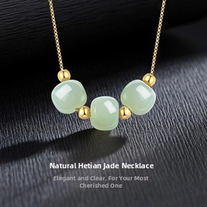 Macro shot of three light green jade squares and gold beads on a delicate chain