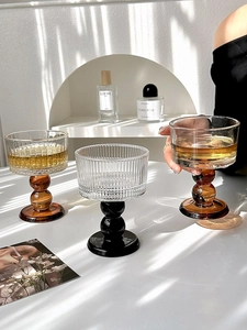 Detailed close-up of ribbed glass goblets with amber and black bases in elegant setting