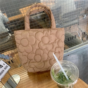 Close-up of khaki quilted tote bag with floral patterns on a wooden table in a cafe