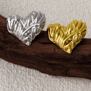 Close-up of gold and silver heart earrings with textured lava pattern on wood