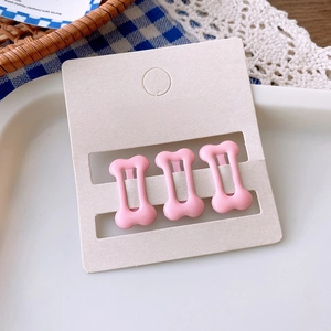 Close-up of three pink bone-shaped hair clips on display card with cute aesthetic