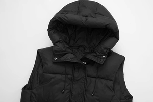 Detail of black hooded puffer vest showing quilted fabric texture and metal snap buttons