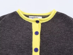 Detailed view of color block knit cardigan with dark grey body and yellow contrast collar