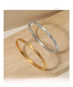 Detail showing gold and silver wavy bangles with rhinestones on a stone background