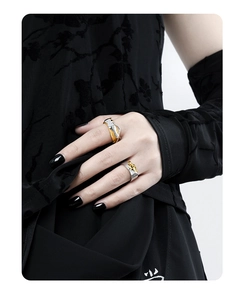 Detailed view of dual-tone textured silver rings with animal motifs on model fingers