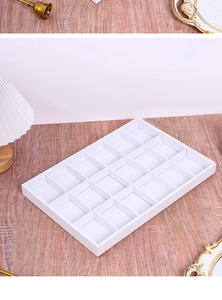 Detailed view of white 18-grid jewelry display tray for rings on a wooden surface